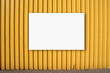 Empty white horizontal advertise banner fixed on yellow metal fence over pavement at city street outside. Business and industrial advertisement.