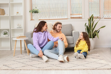 Young family sitting on soft carpet at home