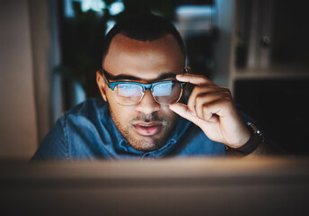 Fototapete - Right, lets do this. Shot of a young businessman using a computer during a late night at work in a modern office.