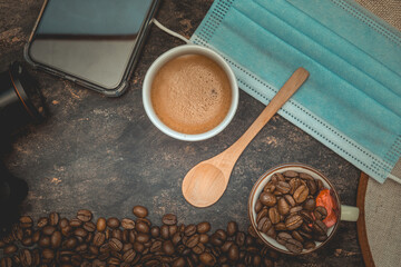 Canvas Print - Top view of a table with coffee, coffee beans, a covid mask, and technology