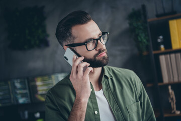 Sticker - Photo of smart thoughtful young man wear green shirt spectacles talking modern device indoors workshop workstation