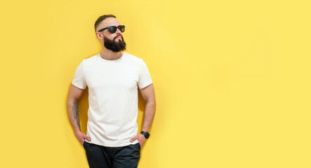 Canvas Print - Young bearded hipster guy wearing white blank t-shirt. Studio shot on yellow background. Mock-up for print. T-shirt template.