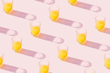 Orange Juice Drinks On A Pastel Pink Background. Aesthetic Juicy Drink Concept With Long Shadow Glasses.