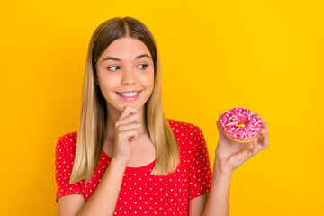 Poster - Photo of young girl hand touch chin think desire look tasty doughnut calories isolated over yellow color background