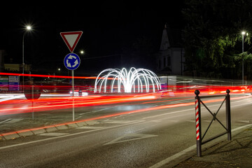 Poster - View of a luminous fountain with car light trails in Italy