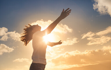 Freedom and hope. Woman raising her arms up to the light golden sunshine. 