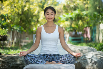 woman meditating in yoga pose. Young woman practicing lotus asana in garden. Asia make yoga therapy and relax.