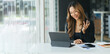 © PaeGAG - Happy young Asian woman sitting at desk at work and using laptop computer for video call