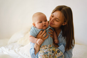 Wall Mural - A young mother is play with little baby boy. Mother of a nursing baby. Happy motherhood. The family is at home. Portrait of a happy mother and child.