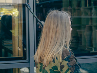 caucasian blond teen aged soldier girl  on a checkpoint holding a rifle gun and wearing a camo green military uniform during a conflict in a war zone