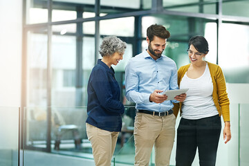 The never get tired of the office tablet. Shot of a group of creative businesspeople looking at a tablet together in the office.