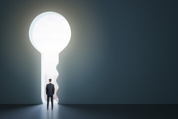 back view of man standing in abstract key opening in wall with bright light and mock up place. solut