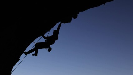 Wall Mural - rock climber climbs a difficult route on a rock in the form of an arch