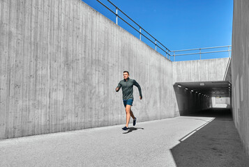 Wall Mural - fitness, sport and healthy lifestyle concept - young man running out of tunnel