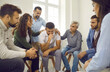 © Studio Romantic - Variety of people provide psychological support to a sad male patient during a group therapy session. Upset young man experiences pain, depression or addiction. Concept of psychological care.