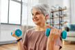 © Syda Productions - sport, fitness and healthy lifestyle concept - smiling senior woman with dumbbells exercising at home