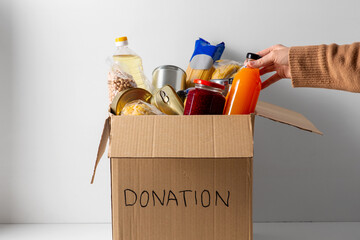 Wall Mural - charity, support and concept - close up of food in donation box and hand