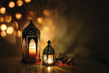 Decorative Arabic Lanterns With Burning Candles At Night. Glittering Golden Bokeh Lights. Festive Greeting Card, Invitation. Muslim Holy Month Ramadan Kareem. Dark Background With Olive Branch.