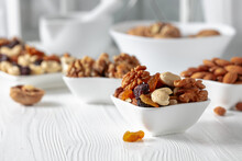 Mix Of Nuts And Raisins On A White Wooden Table.
