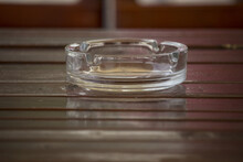 Glassy Ashtray On A Wooden Table With Reflection