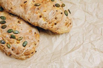 There are two loaves of bread with some seeds on the paper.