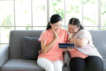 Wall Mural - mother using tablet computer with a girl down syndrome or her daughter, smiling and enjoying on sofa