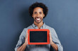 © Nicola K/peopleimages.com - Special message just for you. Portrait of a happy young man holding up a small chalk board on a gray background.