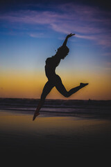 Poster - Vertical photo of a silhouette of a young woman dancing in the air