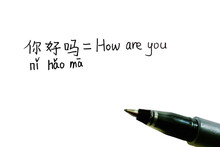 Handwritten Chinese Characters With Pinyin Of "How Are You" And Its English Translation With A Pen