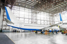 Passenger Aircraft On Maintenance Of Engine And Fuselage Repair In Airport Hangar. View Airplane Completely From Behind To Tail.