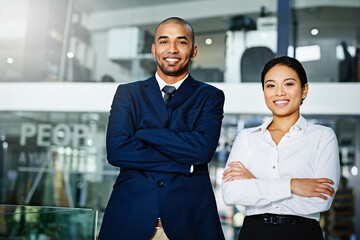 Sticker - Were the perfect team. Portrait of two young businesspeople standing with their arms folded in the office.