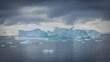 Hintergrundbild, ein strahlend weiß blauer Eisberg treibt im seichten Wasser der Antarktis