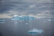 Hintergrundbild, eine gigantische weiß blaue Eisscholle treibt mit anderem Eis im seichten Wasser der Antarktis