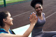 © etonastenka - Two different African and Iranian girlfriends give five to each other while exercising. Sports young women cheering outdoors together for fitness classes on the street. Close-up