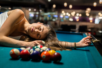 Wall Mural - charming woman in a white T-shirt lies on a pool table