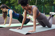 © etonastenka - Two multiethnic fitness women do push-ups in the outdoor stadium. Warm up before workout.