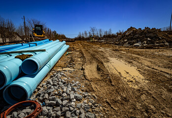 Sewer pipes ready to be buried underground prepared on muddy construction site