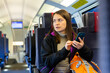 © JackF - Caucasian woman using her smartphone while traveling by train.