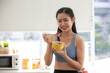 © chokniti - young Asian woman cooking vegetable healthy food and eating or drinking in home kitchen