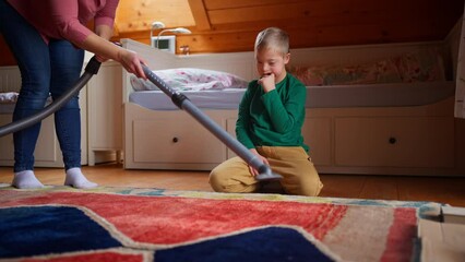 Wall Mural - Boy with Down syndrome with his mother vacuum cleaning at home