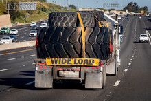 Heavy Equipment Tires Being Hauled On A Flatbed Trailer With A Wide Load Sign