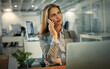 © Thurstan H/peopleimages.com - Just calling to say Ill be working late. Shot of a businesswoman talking on her phone during a late shift at work.
