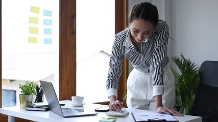 Wall Mural - Female accountant standing and using calculator at office desk.