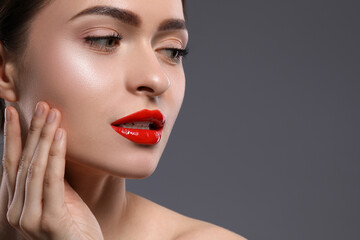 Wall Mural - Young woman with beautiful red lips on grey background. Space for text