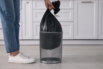 Wall Mural - Woman taking garbage bag out of bin at home, closeup