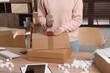 Seller taping parcel at table in office, closeup