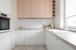 Kuchnia w minimalistycznym nowoczesnym stylu. Białe i różowe fronty mebli oraz sprzęt. 