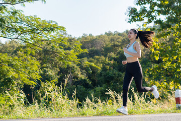 Asian woman jogging outdoors, healthy lifestyle in the park among colorful green leaves. Female runner jogging, beautiful, fit, fitness, mixed, fitness, model, outdoor