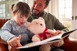 © Monkey Business - Father With Down Syndrome Daughter Reading Book At Home Together