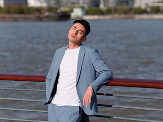 portrait of handsome chinese young man in light blue suit and white undershirt standing with eyes cl